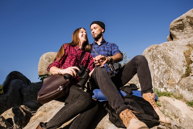 Un couple de voyageurs hipster assis ensemble sur les rochers dans les montagnes