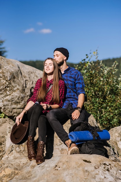 Un couple de voyageurs hipster assis ensemble sur les rochers à la montagne