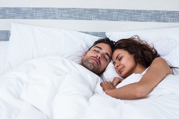 Couple avec les yeux fermés tout en se relaxant sur le lit