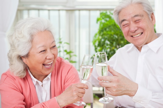 Couples aînés, grillage, verres champagne