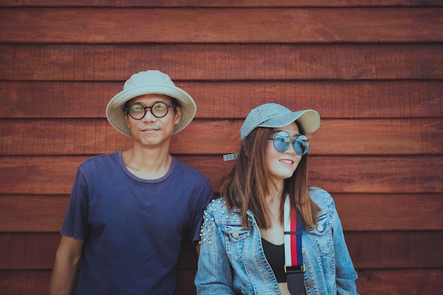 Couples asiatiques portant des vêtements chapeau et style de vie décontracté debout contre un mur en bois