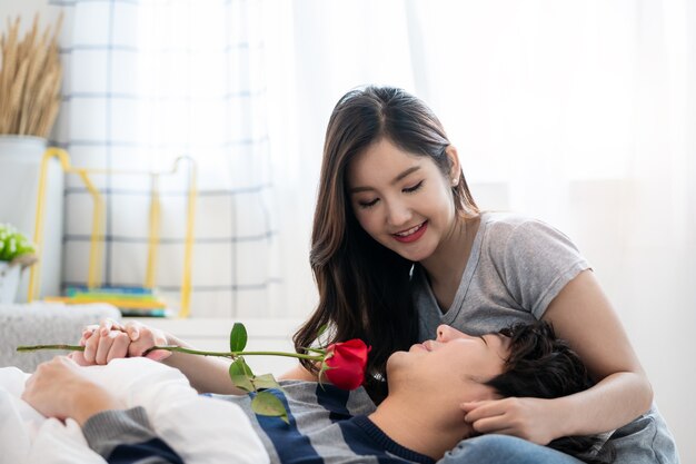 Couples asiatiques romantiques dans la chambre un jeune homme donnant une rose rouge à une jolie femme