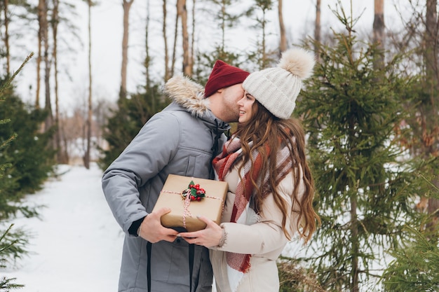 Couples Câlins Et Bisous Dans Une Forêt De Conifères D'hiver, Offrez-vous Des Boîtes Avec Des Cadeaux