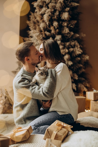 Couples célébrant Noël avec leur chat par l'arbre de Noël