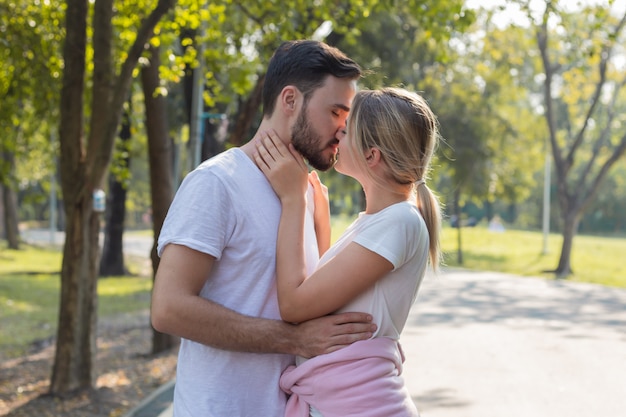 Couples debout baiser et étreindre dans le parc.