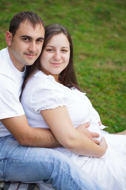 Les couples enceintes sont assis sur l'herbe dans le parc