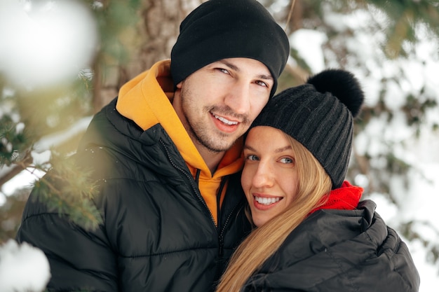 Couples heureux étreignant et souriant dehors dans le parc enneigé