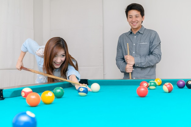 Des couples heureux jouent au billard à la maison,