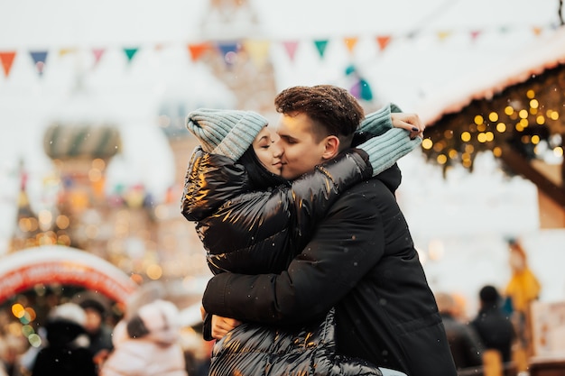 Couples heureux sur la place de la ville décorée pour un marché de Noël étreindre et s'embrasser