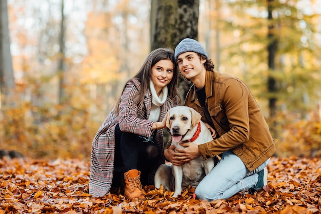 Couples heureux romantiques amoureux profitant de leur temps avec le labrador dans le parc d'automne