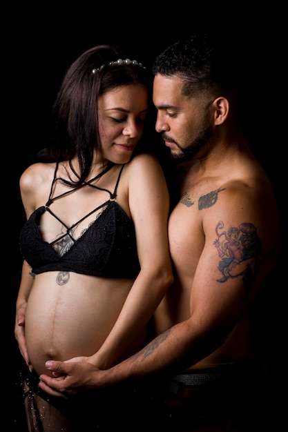 Couples latino-américains avec la femme enceinte et s'embrassant sur fond noir