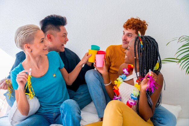 Couples lgtb de garçons et de filles gays lesbiennes dans un portrait sur un canapé lors d'une fête d'anniversaire à la maison portant un toast avec des lunettes