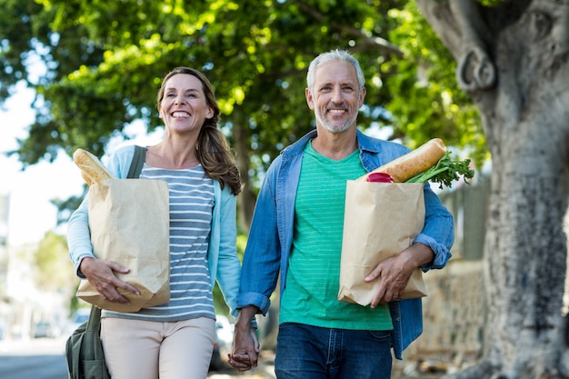 Couples mûrs, tenue, sacs provisions, par, arbre