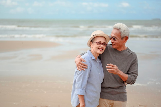 Les couples de personnes âgées embrassent la plage du lever du soleil, planifient une assurance-vie avec le concept de retraite heureuse.