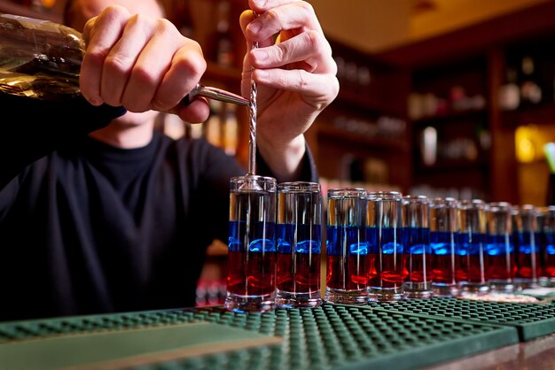 Coups d&#39;alcool sur le comptoir. Le barman professionnel verse des coups alcoolisés.