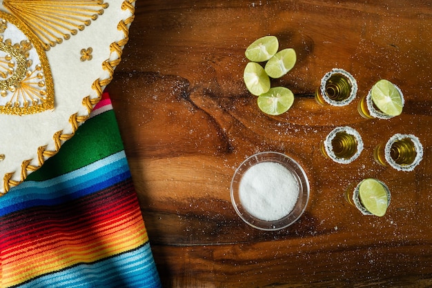 Des coups de tequila avec du sel et du citron sur une table en bois.