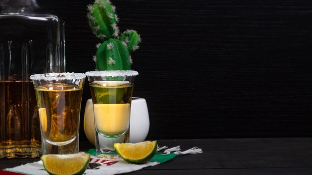 Coups de tequila mexicains accompagnés d'une bouteille carrée de luxe sur une table en bois avec des citrons