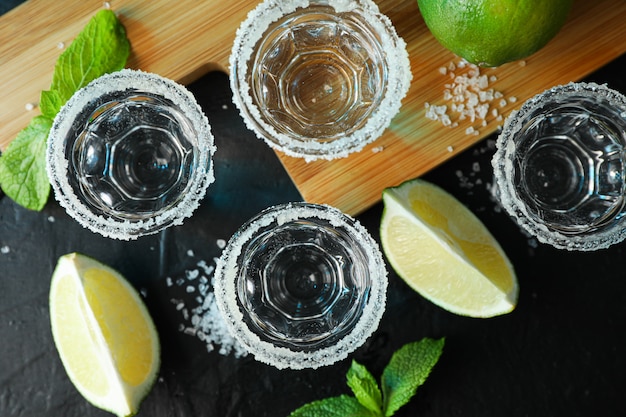Coups de Tequila avec sel, tranches de citron vert et menthe sur tableau noir