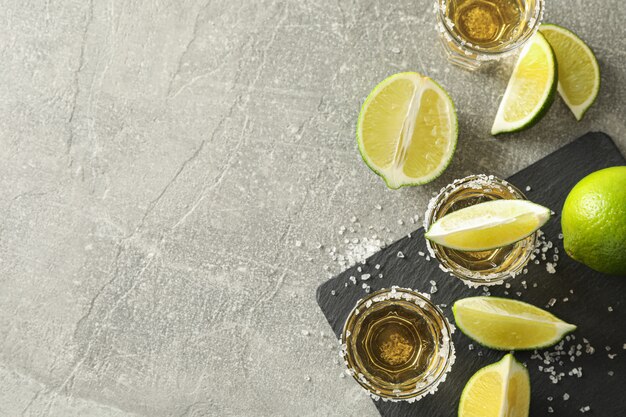 Coups de Tequila avec des tranches de sel et de lime sur fond gris