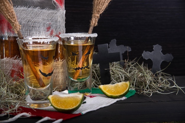 Coups de tequila avec des verres de bouteille bandés de décoration d'halloween avec des visages effrayants et des balais de sorcières