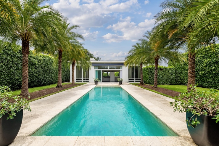 Photo la cour arrière d'une maison moderne avec piscine, gazon artificiel, chemin en pierre, arbres, chaises et ombrelle