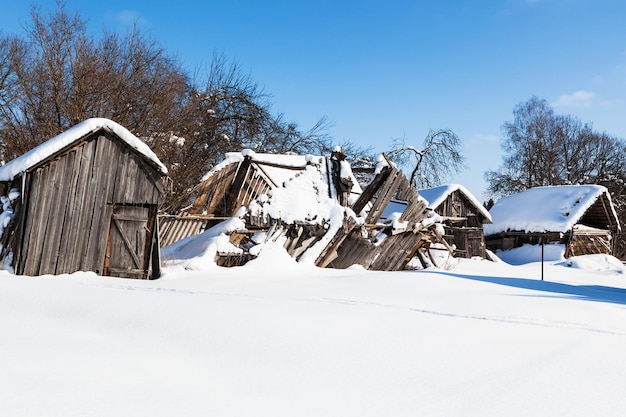 Cour en ruine couverte de neige dans le village en hiver