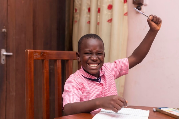 Courageux jeune écolier africain rassemblant joyeusement un bras finissant ses travaux scolaires