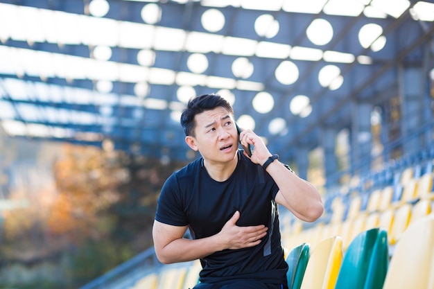 Le coureur asiatique masculin a des douleurs thoraciques sévères des maux de coeur après avoir couru et s'être entraîné en appelant une ambulance appelle un médecin rapidement