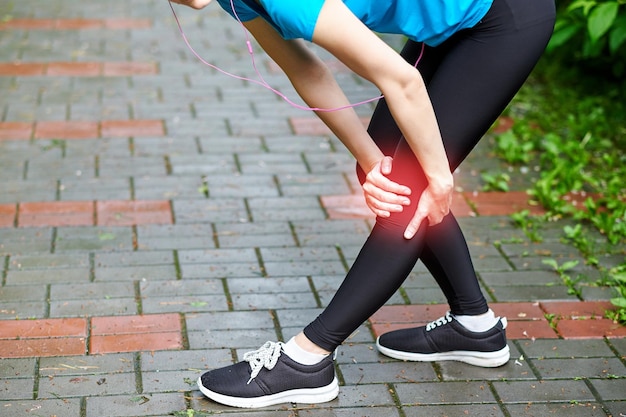 Coureur d'athlète femme touchant le genou dans la douleur fitness femme courant dans le parc d'été mode de vie sain et concept de sport