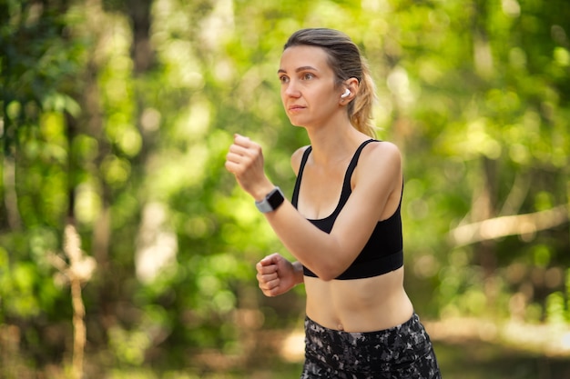 Coureur de belle jeune femme dans une forêt verte.