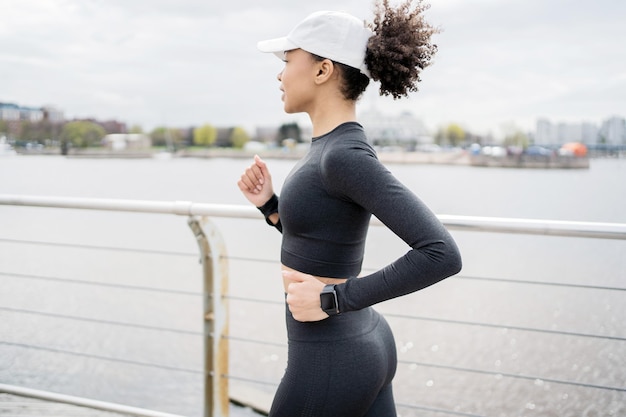 Un coureur est une femme sportive faisant une séance d'entraînement en utilisant une montre de suivi de bracelet de fitness sur son bras