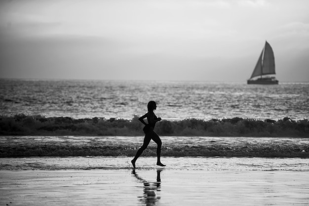 Coureur femme courant sur la plage au coucher du soleil