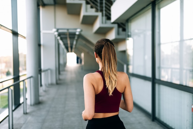 Coureur de femme jeune sportif en cours d&#39;exécution à l&#39;intérieur. Vue arrière.