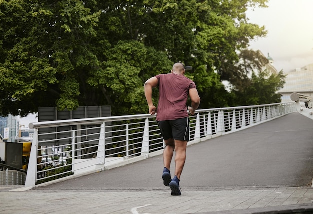 Coureur de fitness et homme sur un pont pour s'entraîner au bien-être et au cardio dans une ville cardio et énergie Coureur sportif et exercice masculin sur une autoroute pour un défi de course et des objectifs de performance corporelle