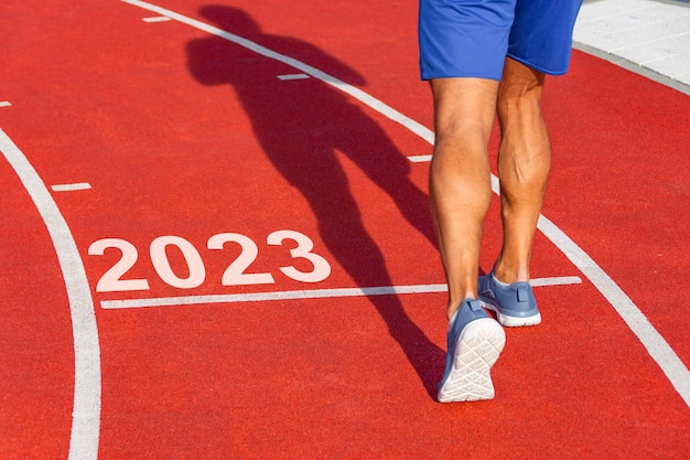 Le coureur franchit la ligne à partir de 2023 sur un tapis roulant rouge avec les numéros 2023 Étape du concept d'entrée du nouvel an