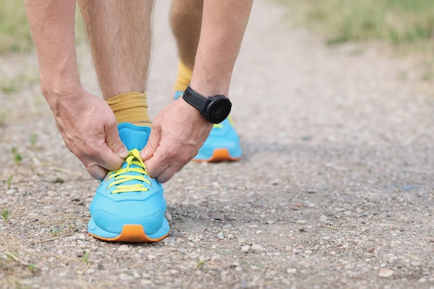 Le coureur d'homme attache des lacets au sol avec le concept de sports et de jogging de mains