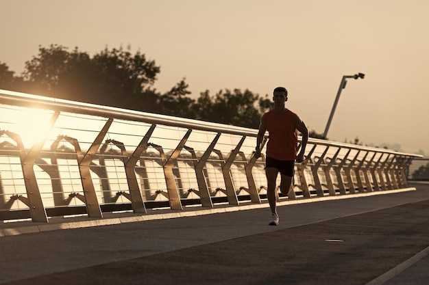 Coureur d'homme en forme athlétique courir sur la promenade en soirée