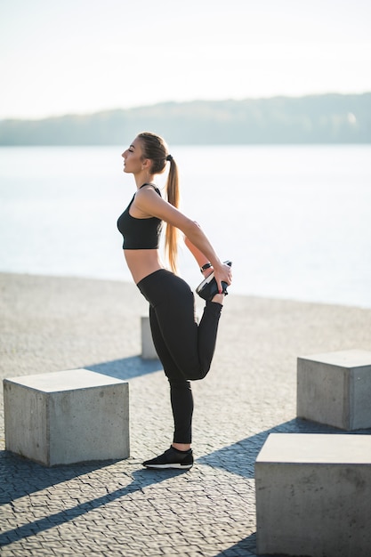 Coureur de jeune femme fitness étirement des jambes avant de courir