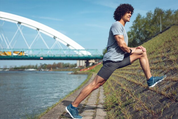 Coureur masculin faisant des exercices d'étirement sur la côte fortifiée, se préparant à l'entraînement du matin.