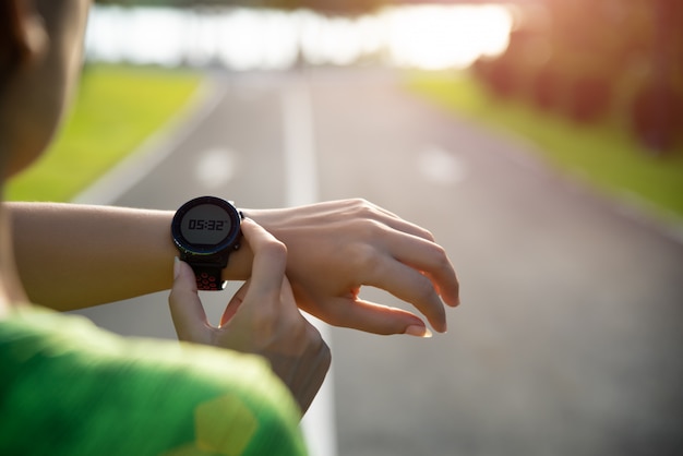 Photo coureur mettant en place une montre intelligente avant de courir au coucher du soleil