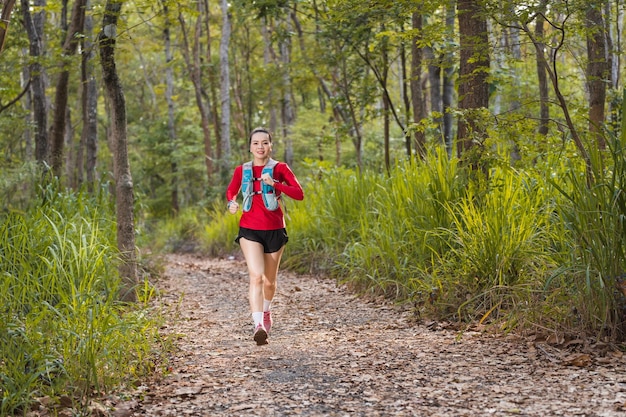 Coureur de piste de jeune sportive de remise en forme courant dans le parc de la forêt tropicale le soir