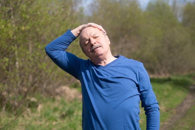 Coureur senior avec brassard faisant des étirements printemps nature