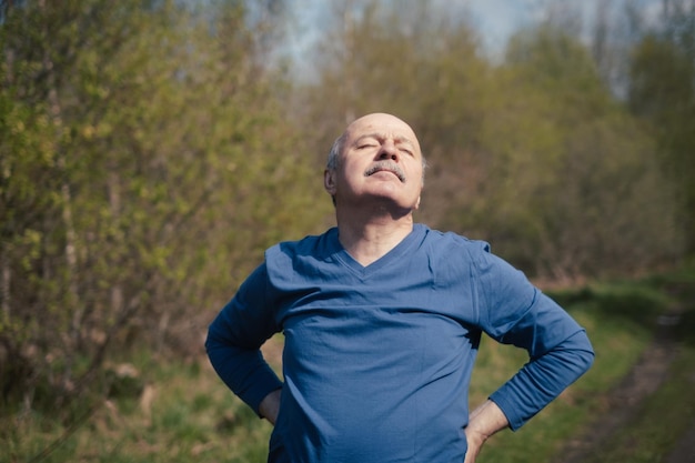 Coureur senior avec brassard faisant des étirements printemps nature