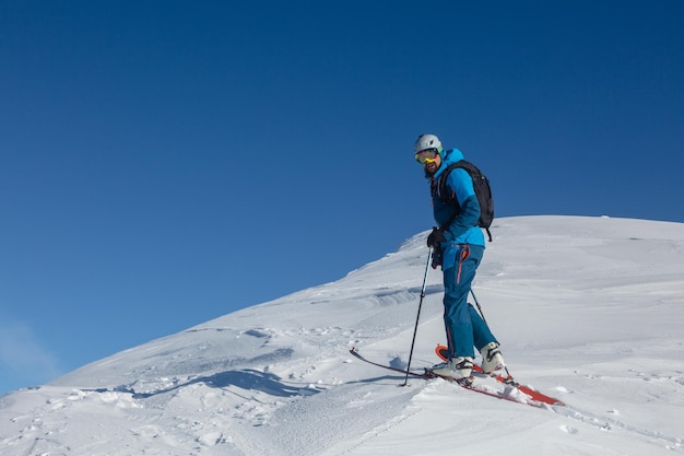 Un coureur de ski de randonnée actif sur un sentier d'hiver au milieu de la chaîne de montagnes