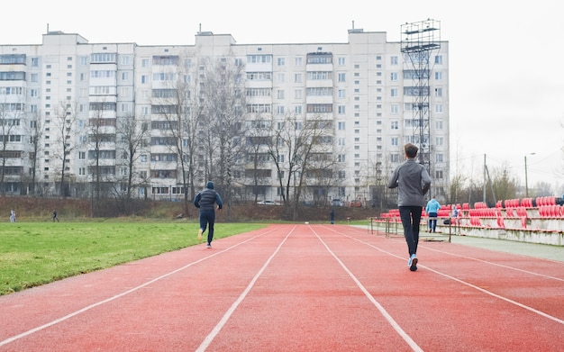 Coureurs amateurs sportifs au stade à l'extérieur, vue arrière. Entraînement en plein air, mode de vie actif.