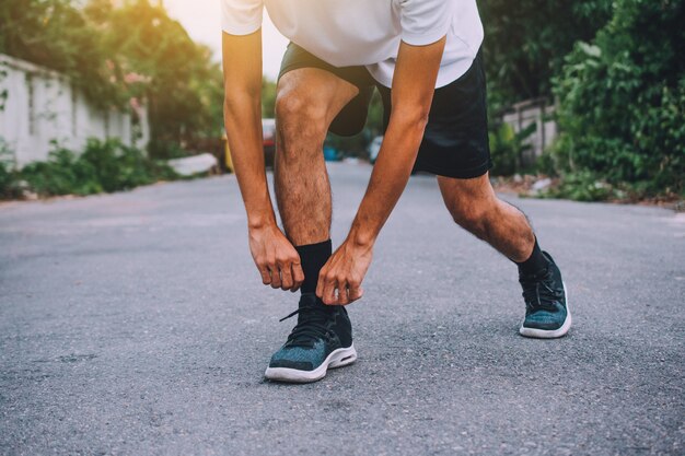 Coureurs à égalité dans les chaussures, homme courir dans la rue soit courir pour l'exercice, exécuter des fond de sport et gros plan à la chaussure de course