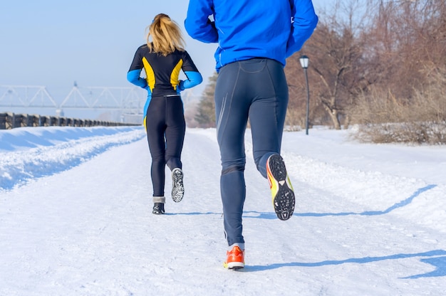 Coureurs. Jambes, vue arrière. Jeunes couples en cours d'exécution. Sport homme & femme jogging sur winter park