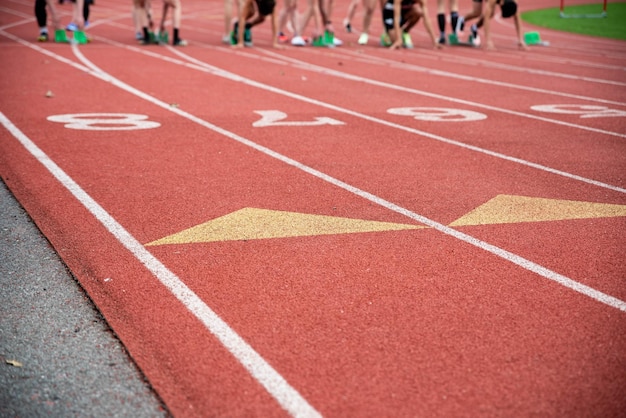 Photo des coureurs à la ligne de départ sur des blocs sur une piste de course athlétique avec des numéros et des marquages de voie