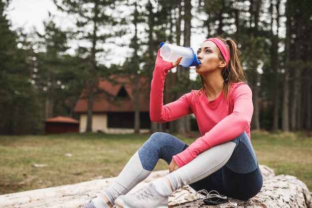 La coureuse boit de l'eau et fait une pause après avoir fait du jogging à l'extérieur