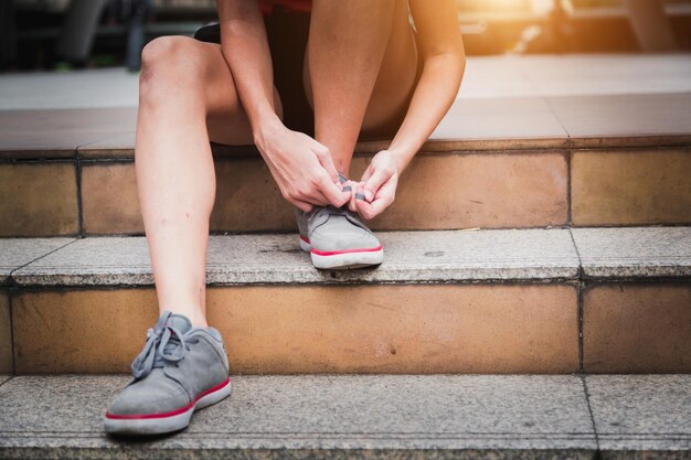 Une coureuse se prépare à courir, attache des chaussures de course, des lacets, un mode de vie sain, une motivation pour le jogging.